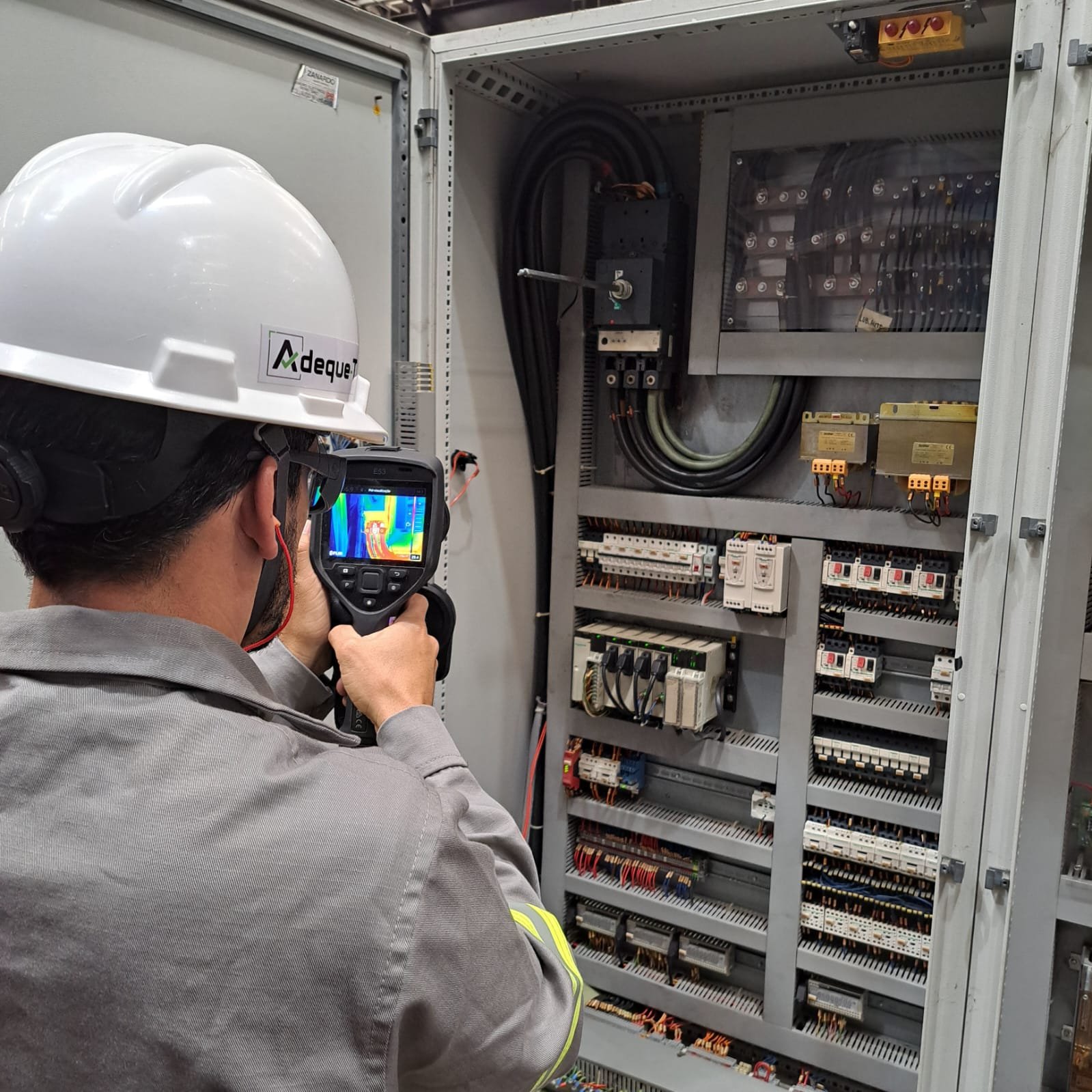 Profissional da Adeque-T realizando inspeção termográfica em painel elétrico industrial