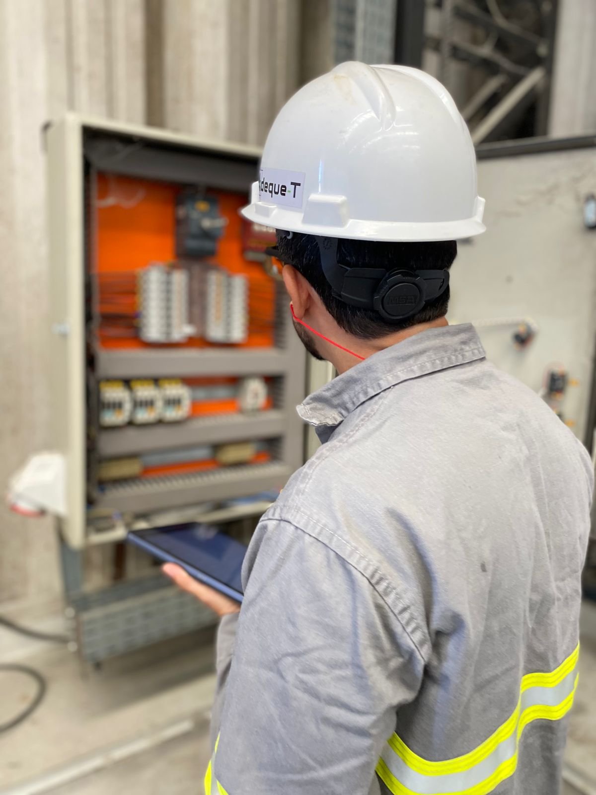 Engenheiro registrando dados técnicos de painel elétrico em ambiente industrial